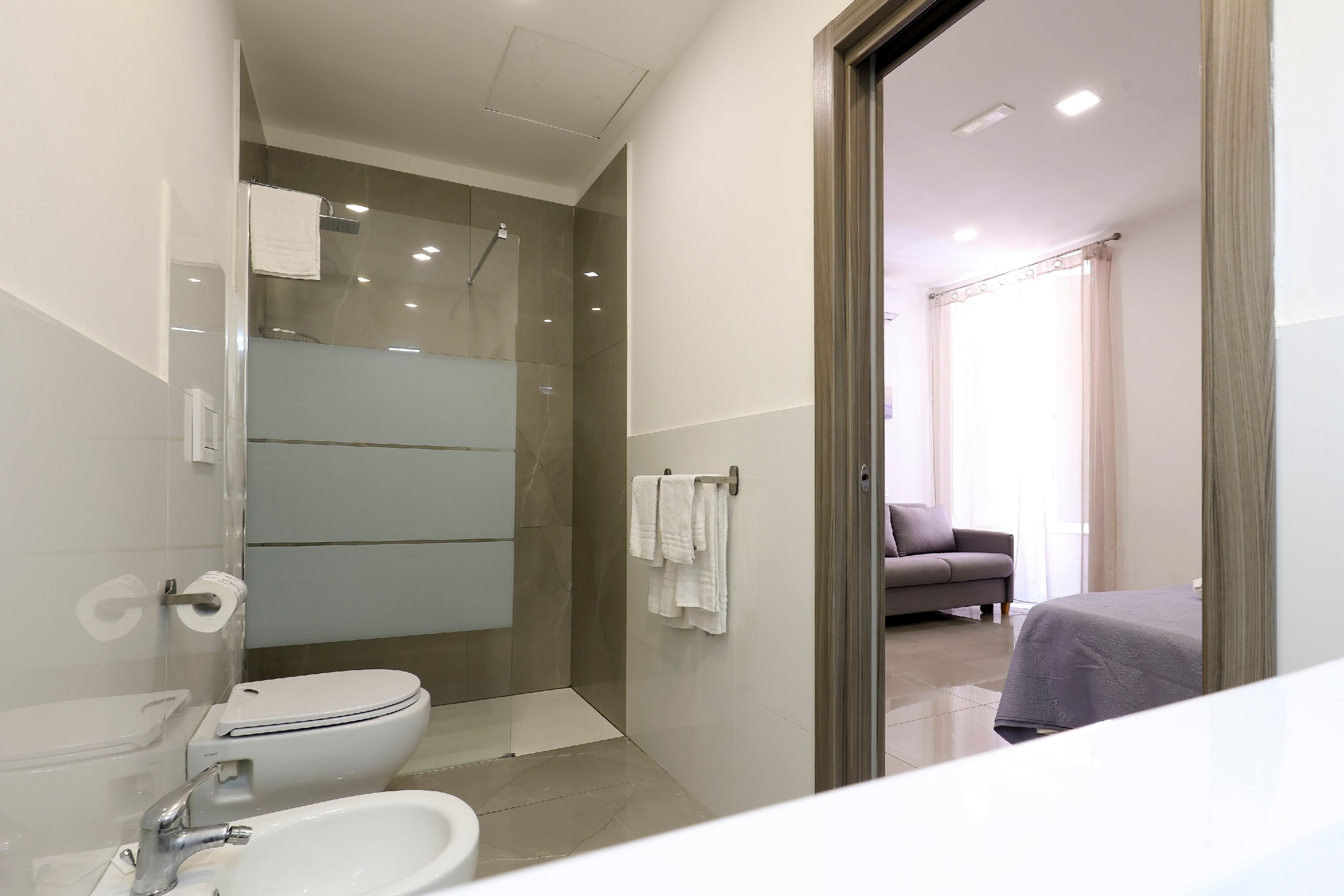 Et moderne badeværelse med toilet, vask og bruser.