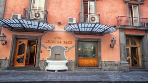 A hotel facade with a classic design, featuring a central entrance with a decorative archway, a sign reading "HOTEL LA PACE," and a balcony with a metal railing. - Hotel La Pace (Naples)