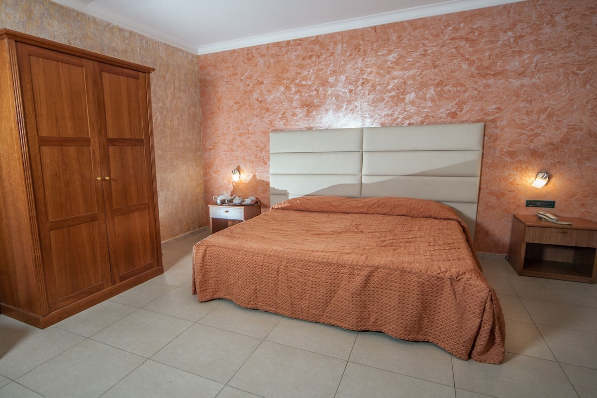 Una camera da letto con un letto grande, un armadio e due comodini con lampade.