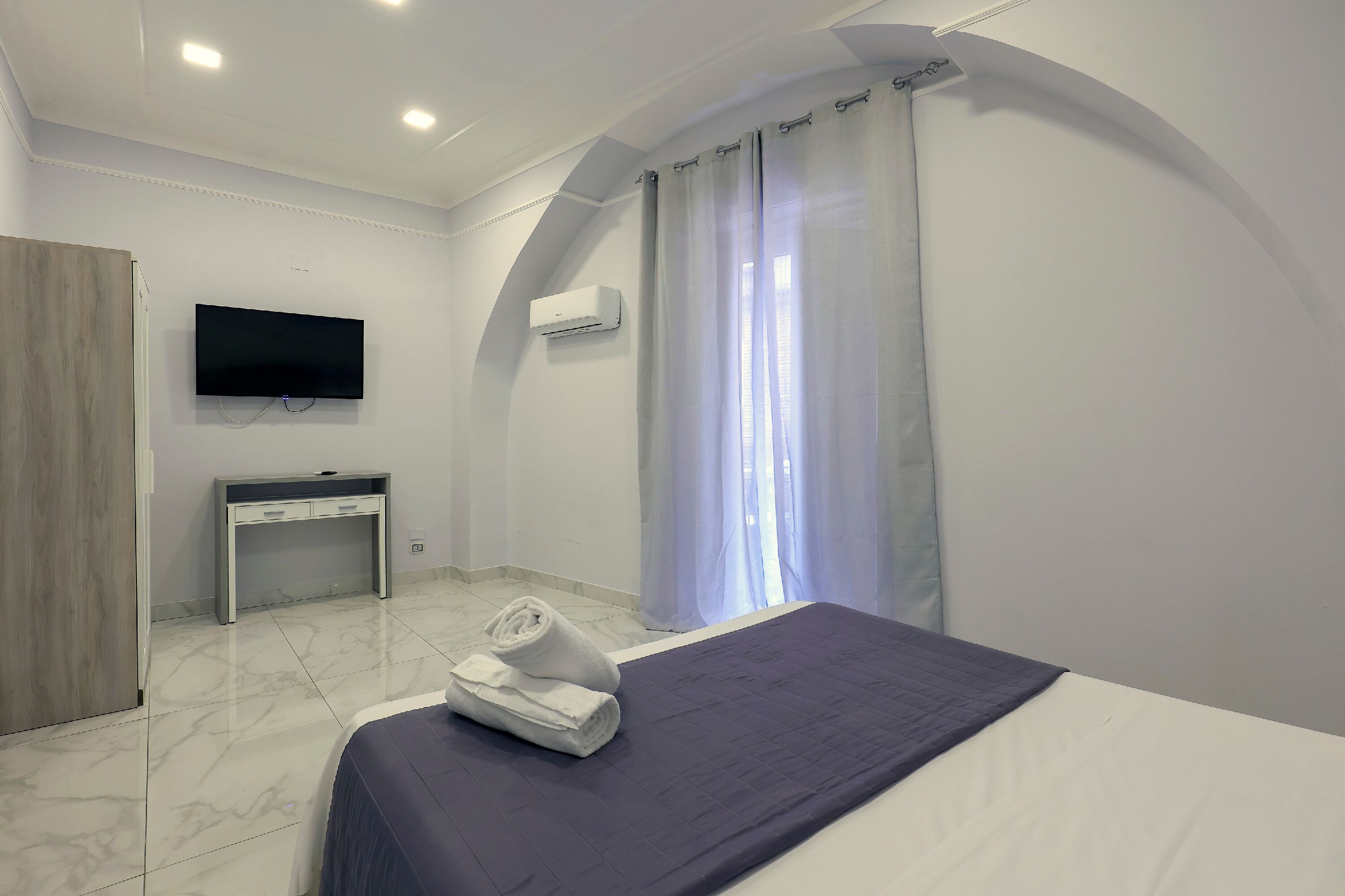 Une chambre d’hôtel équipée d’un lit, d’un bureau, d’une télévision à écran plat et d’un espace douche.