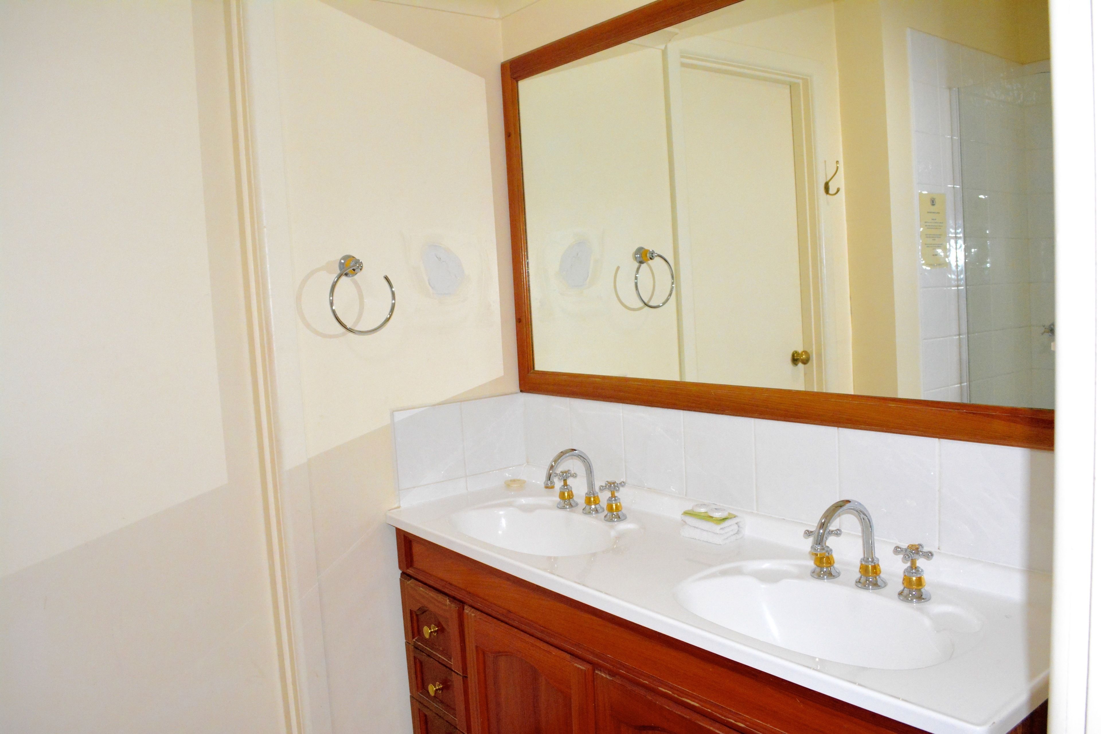 A bathroom with two sinks, a large mirror, and a wooden vanity.
