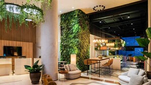 A modern interior with a living area, seating, a bar, and a kitchen area. - Grand Mercure SP Itaim Bibi (São Paulo)