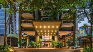 A multi-story hotel with a central atrium, outdoor seating area, and surrounding greenery. - Grand Mercure SP Itaim Bibi (São Paulo)