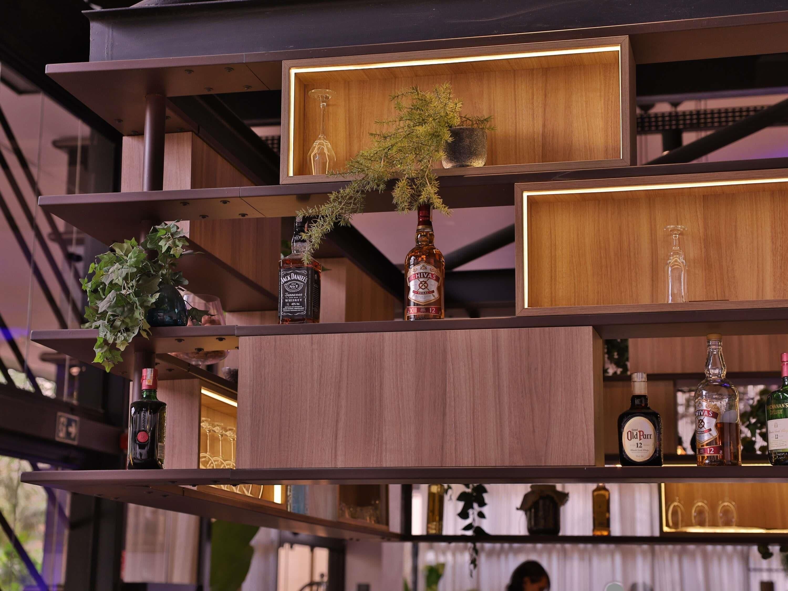 A bar area with shelves holding bottles and a potted plant.