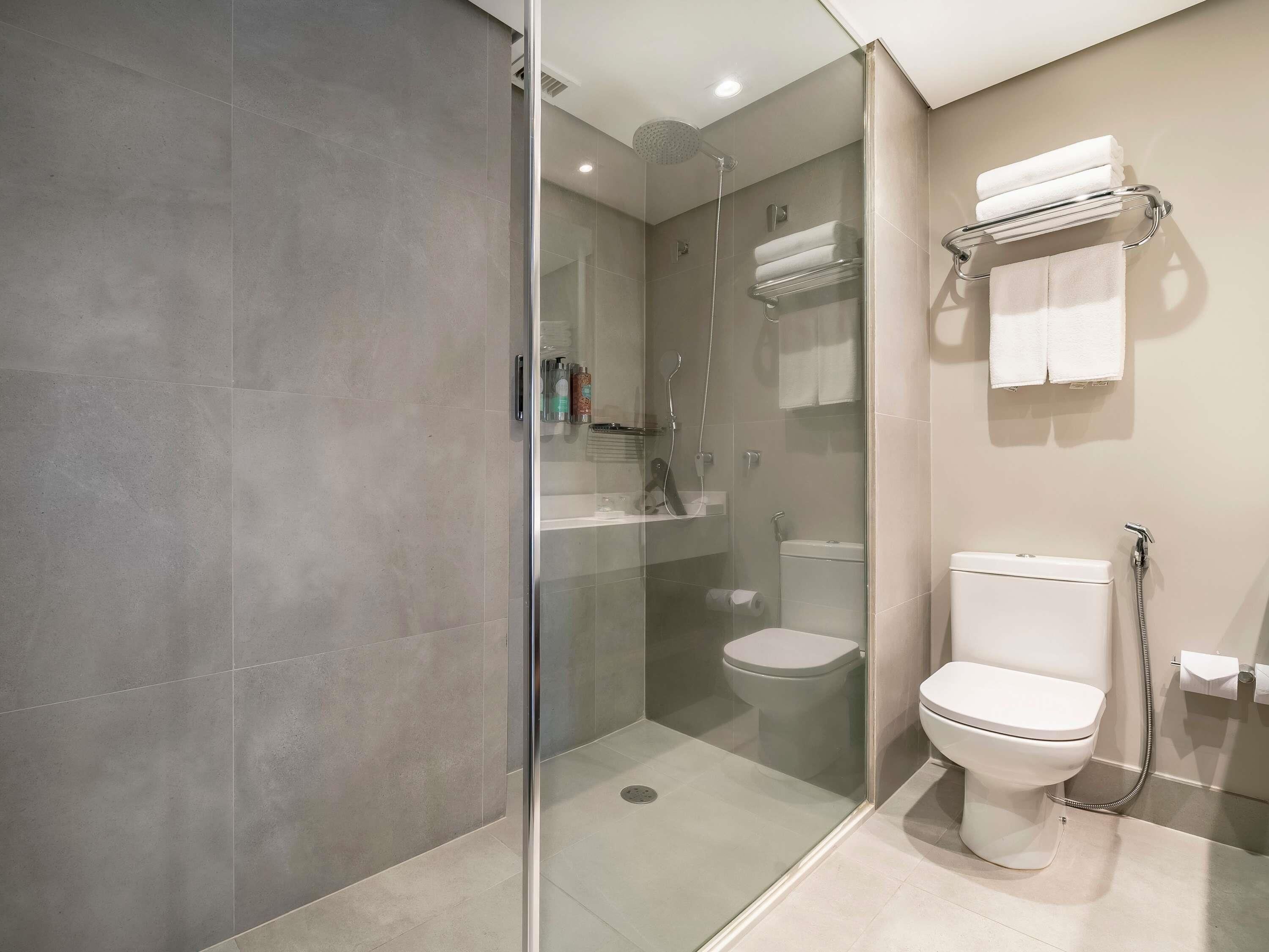 A modern bathroom with a glass-enclosed shower, a toilet, and a towel rack.