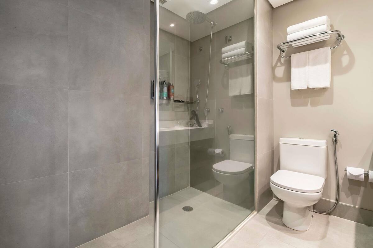 Et moderne badeværelse med en glasafskærmet brusebad, toilet og håndklædestang.