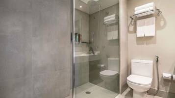 Une salle de bain moderne avec une douche à parois de verre, des toilettes et un porte-serviettes.