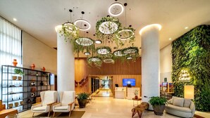 A modern lobby with a reception desk, seating area, and a green wall with hanging plants. - Grand Mercure SP Itaim Bibi (São Paulo)