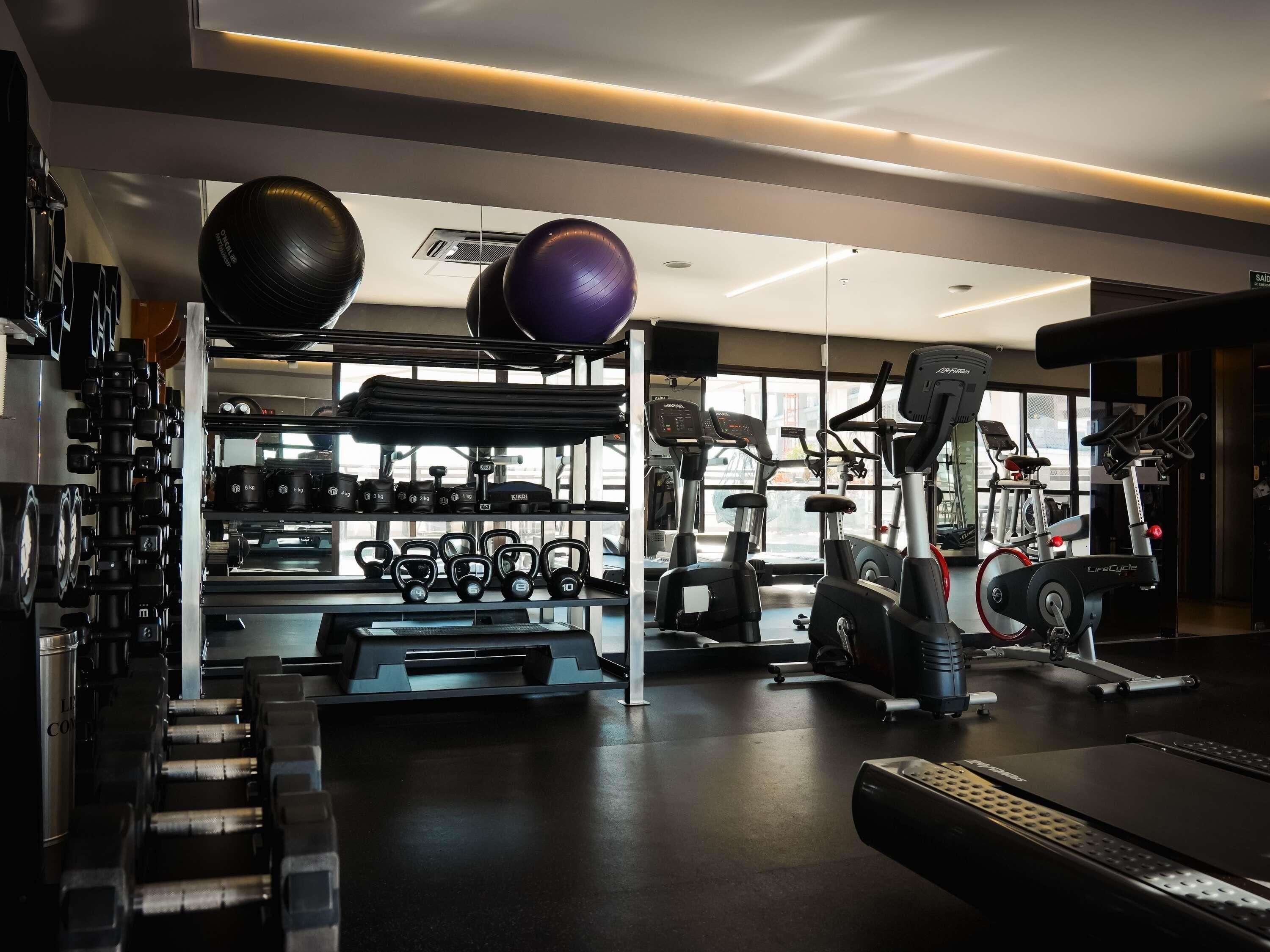 Et moderne fitnesscenter med forskellig træningsudstyr, herunder løbebånd, styrkemaskiner og håndvægte.