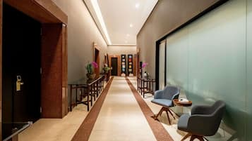 A modern hallway with a marble floor, wooden furniture, and glass partitions.