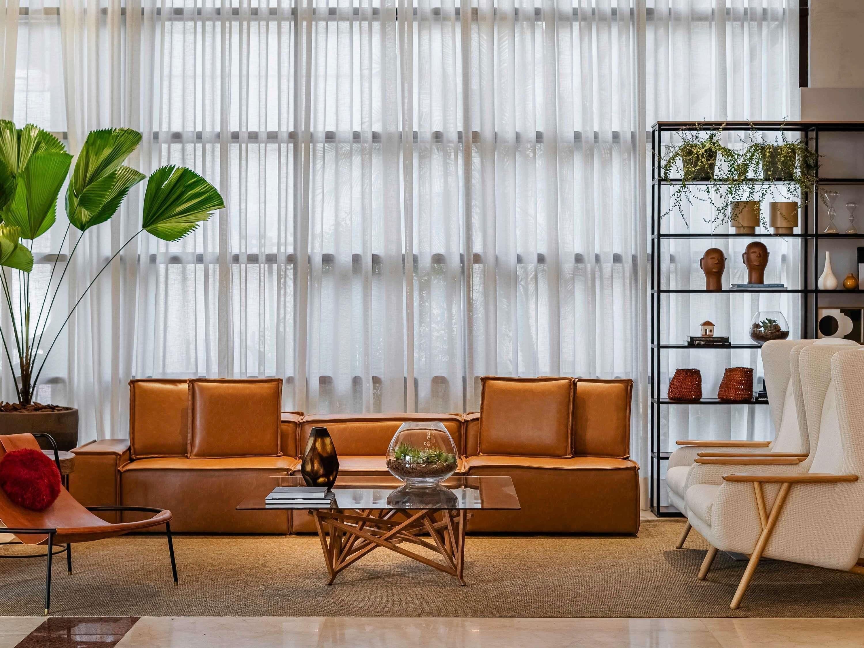 Un salon moderne avec un canapé en cuir, une table basse en verre et une bibliothèque agrémentée d’objets décoratifs.