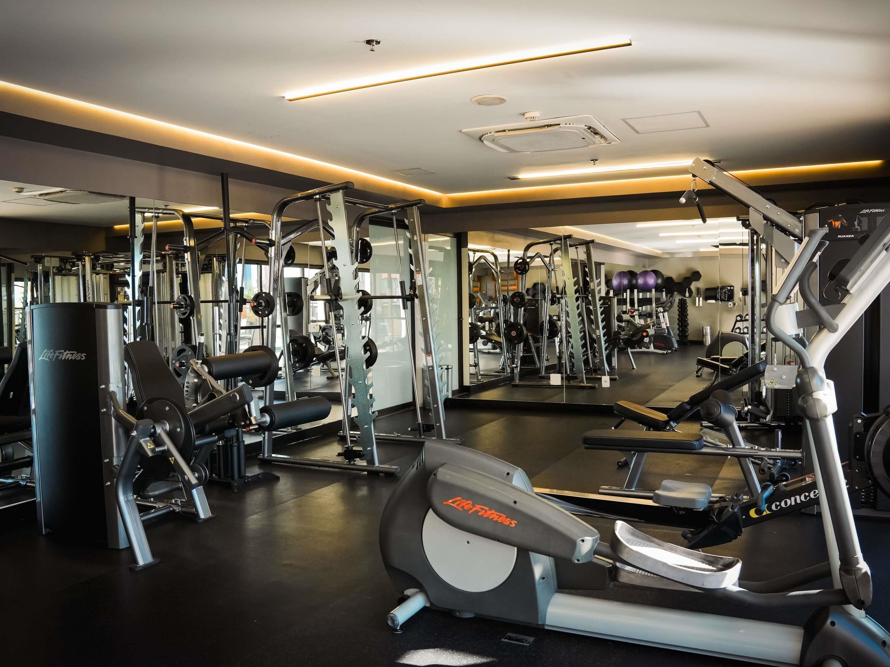 Een sportschool met cardioapparatuur, krachttrainingsmachines en losse gewichten.