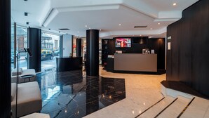 A modern lobby with a reception desk, seating area, and glass doors leading outside. - Bisonte Libertad (Buenos Aires)