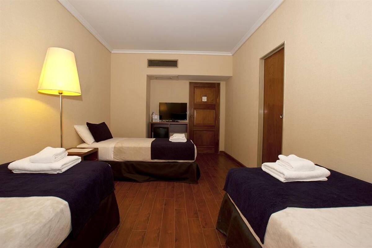 Ein Hotelzimmer mit zwei Betten, einem Schreibtisch, einer Lampe und einem Fernseher.