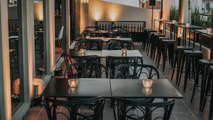 An outdoor dining area with tables and chairs, a bar in the background, and a cityscape view. - Bisonte Libertad (Buenos Aires)