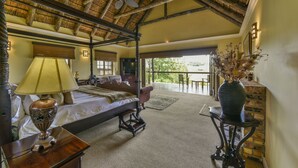 A spacious bedroom with a large bed, a ceiling fan, and a view of the outdoors. - Kwantu Private Game Reserve (Sidbury)
