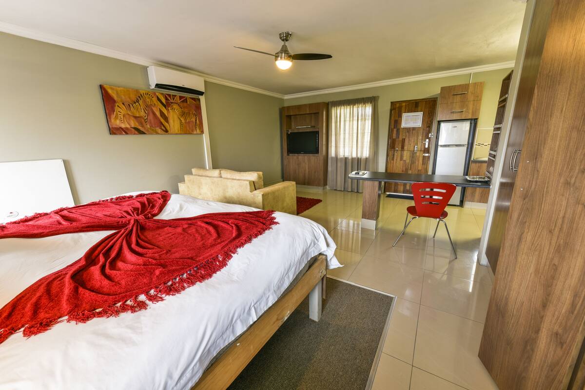Une chambre d’hôtel équipée d’un lit, d’un bureau, d’une chaise, d’un ventilateur de plafond et d’un téléviseur.