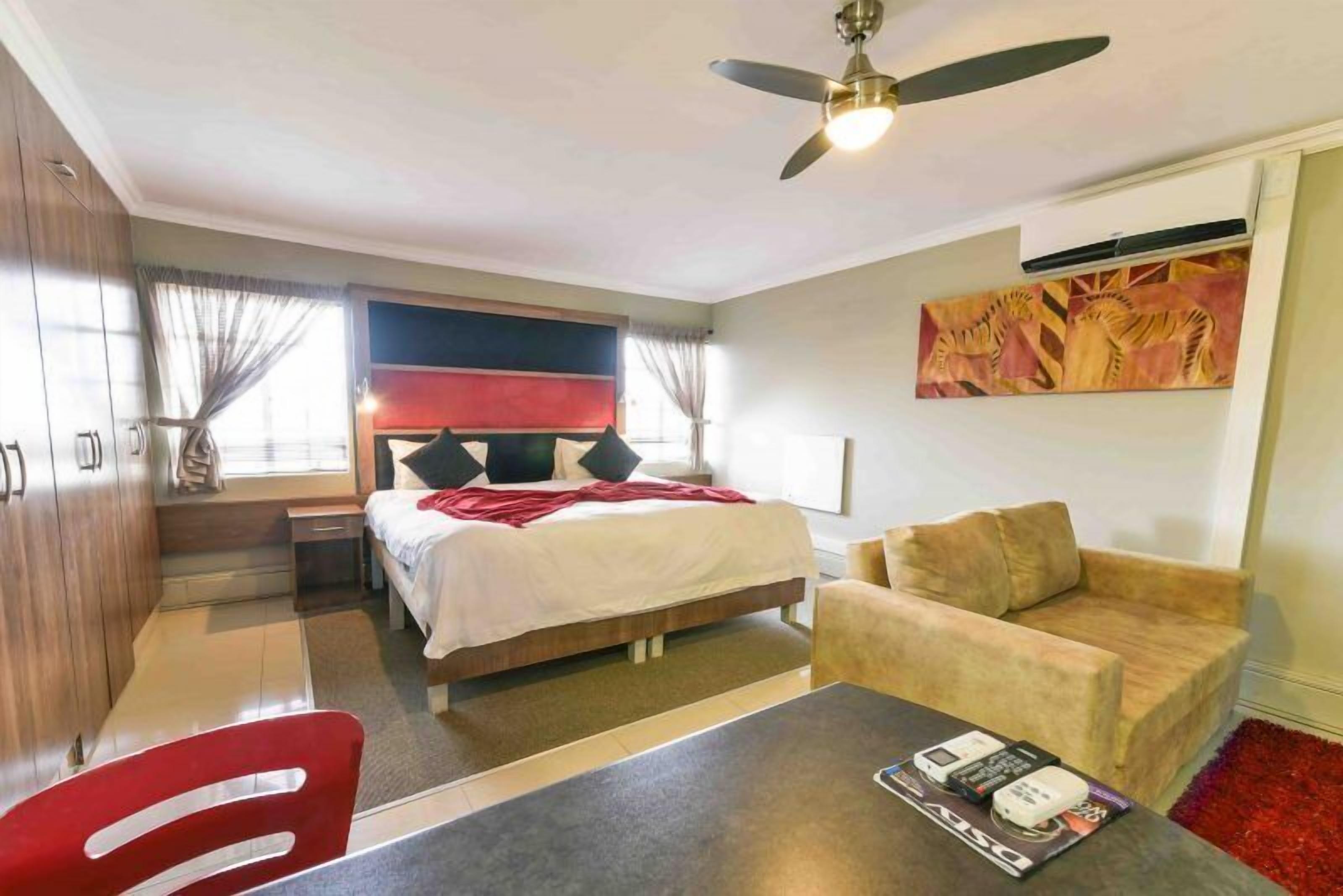 Una habitación de hotel con una cama, un sofá, una mesa y un ventilador de techo.