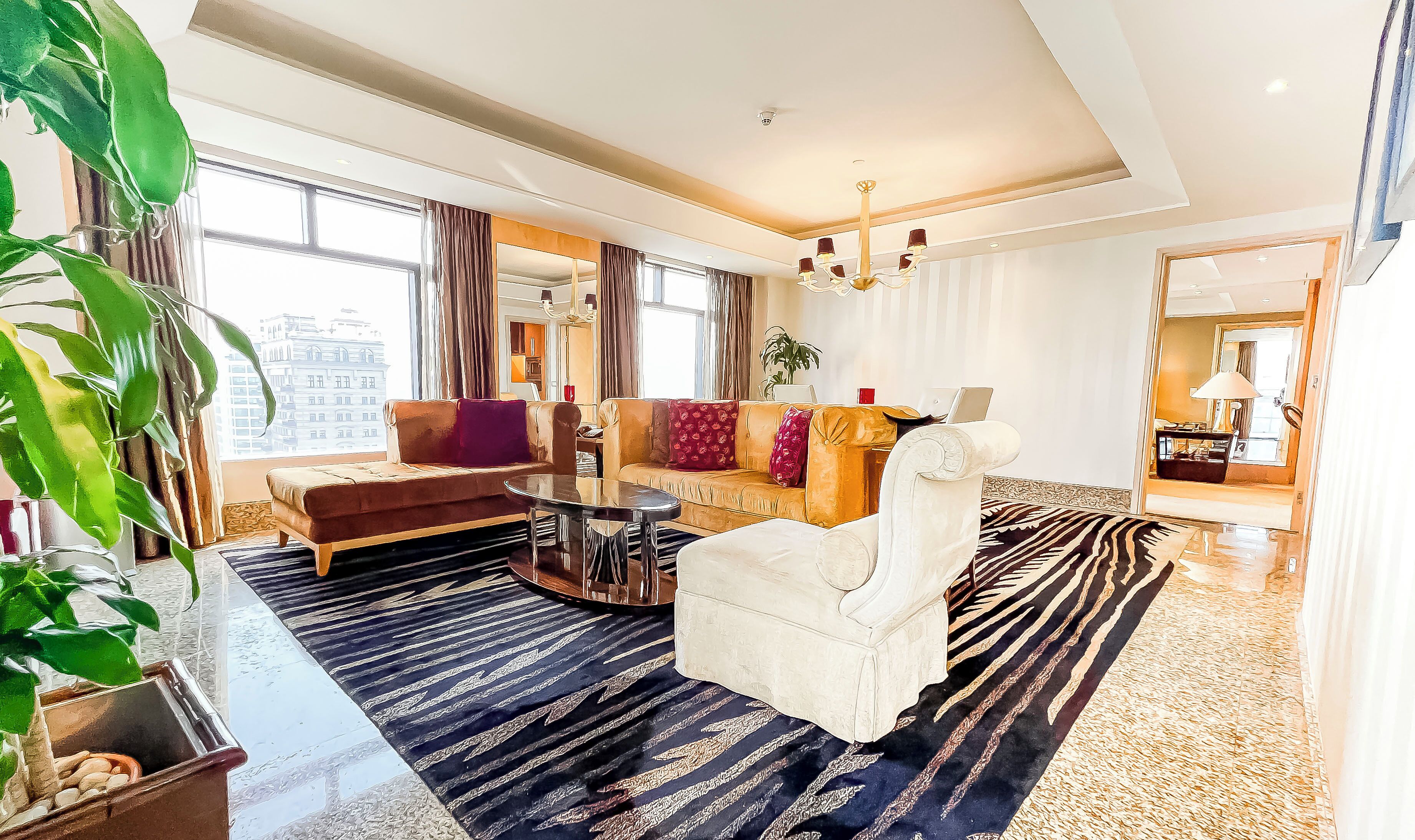 A modern hotel room with a sofa, armchair, and a small table.