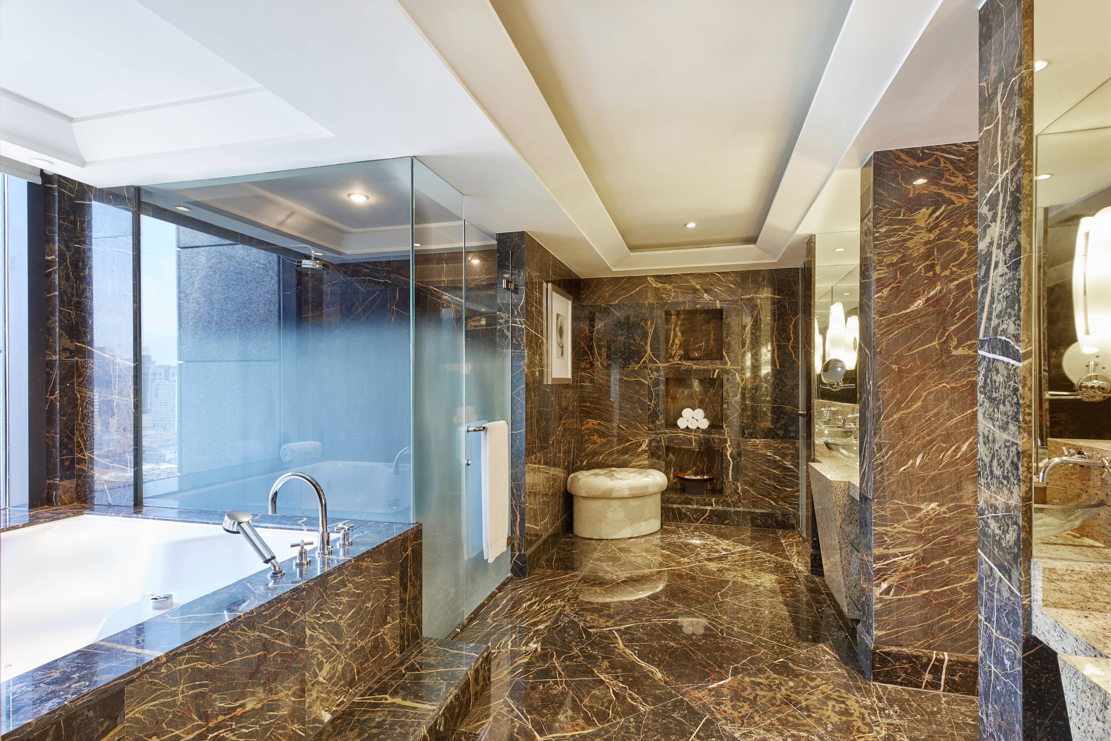 Un baño moderno con ducha envuelta en vidrio, una bañera independiente y suelo de mármol.
