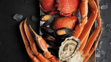 Una bandeja de mariscos con patas de cangrejo, mejillones y ostras sobre una bandeja metálica con hielo.