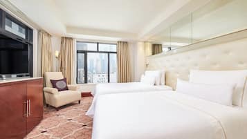 A hotel room with two beds, a TV, a chair, and a large window with a city view.
