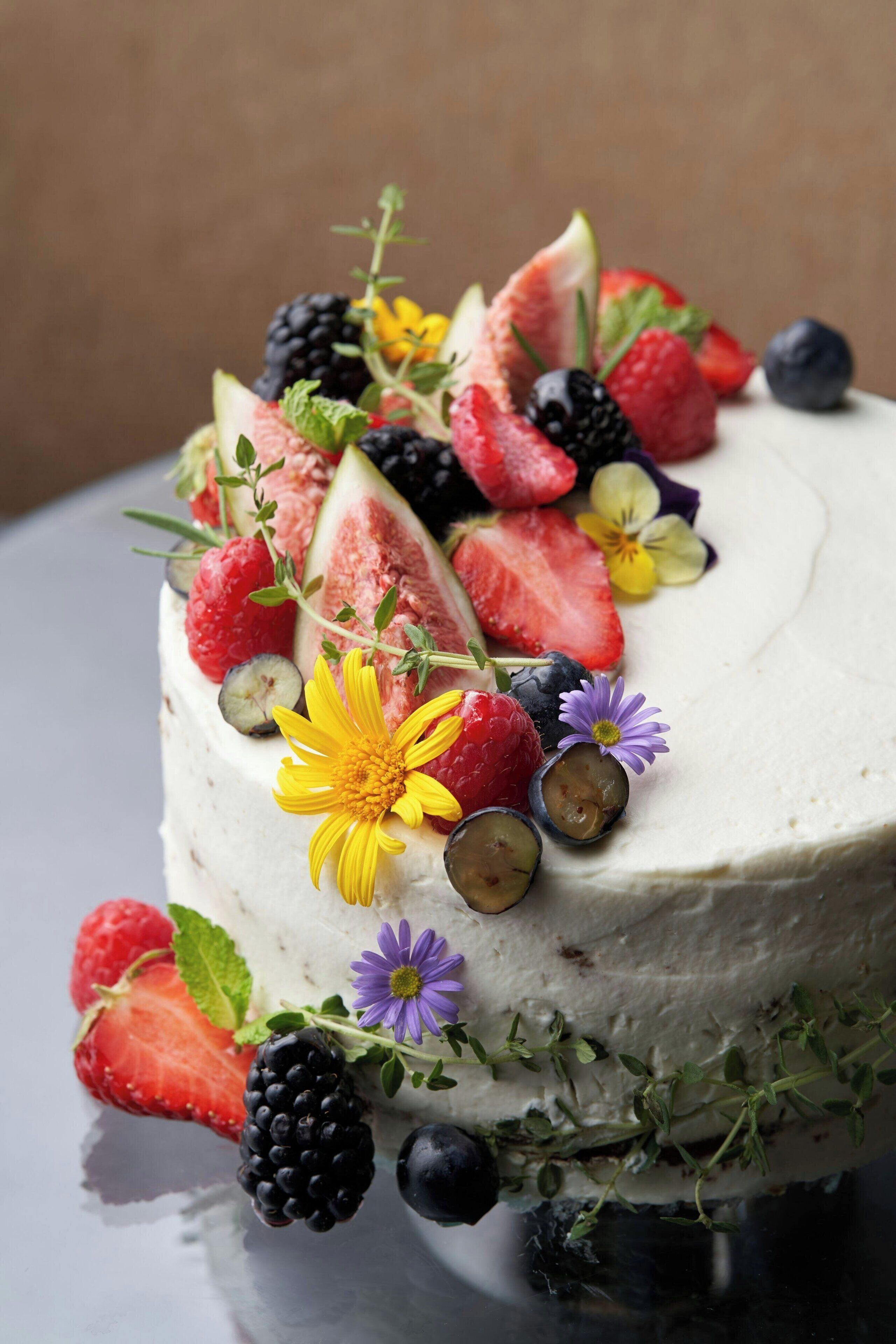 Un gâteau décoré de divers fruits et de fleurs.
