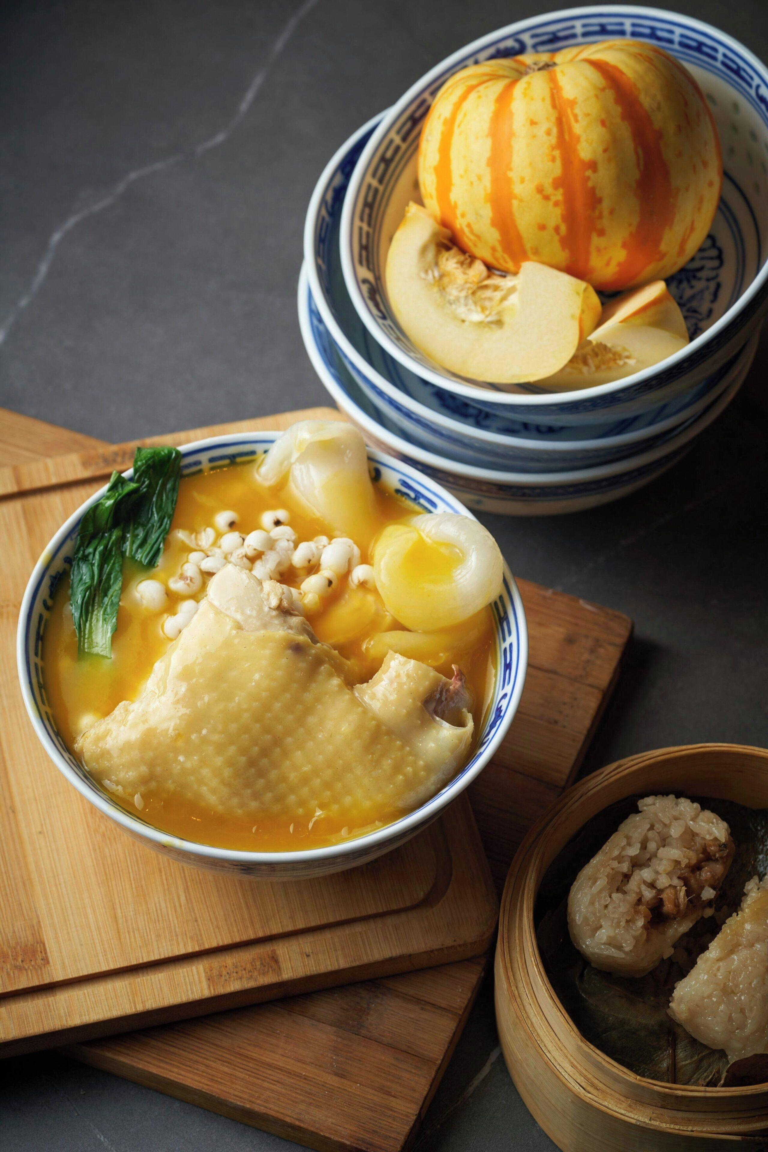 Un tazón de sopa con diversos ingredientes, una calabaza en rodajas y un tazón de arroz.