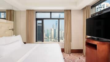 A hotel room with a large bed, a television, and a window offering a city view.