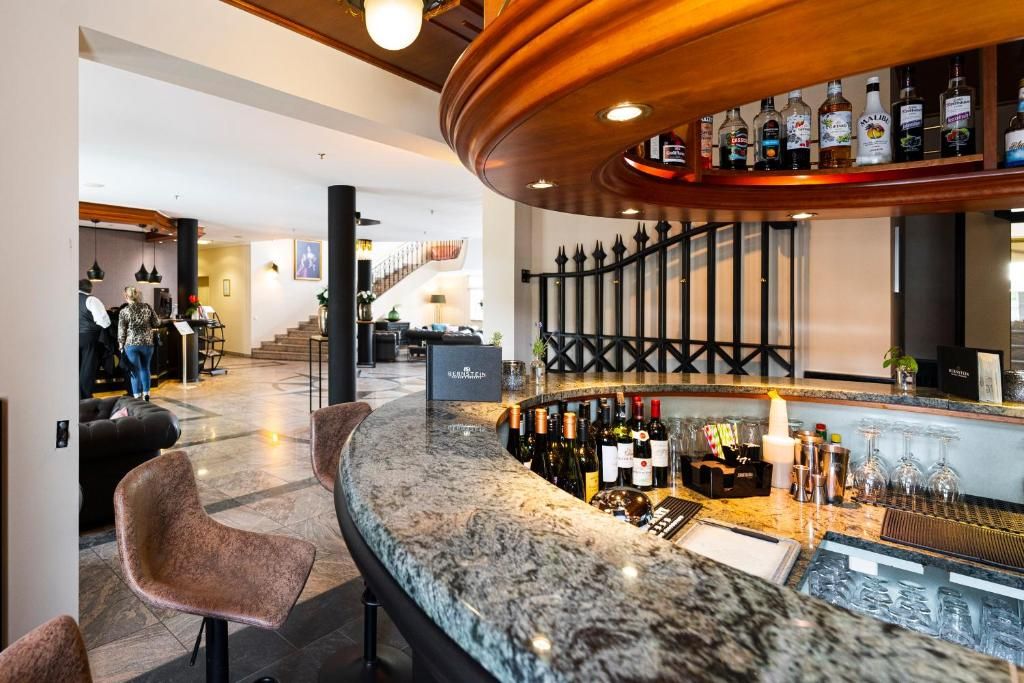 A bar area with a curved countertop, bar stools, and a selection of bottles and glasses.