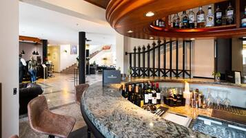 A bar area with a curved countertop, bar stools, and a selection of bottles and glasses.