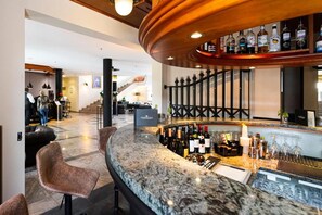A bar area with a curved countertop, bar stools, and a selection of bottles and glasses. - Bernstein Schlosshotel Ballenstedt (Ballenstedt)