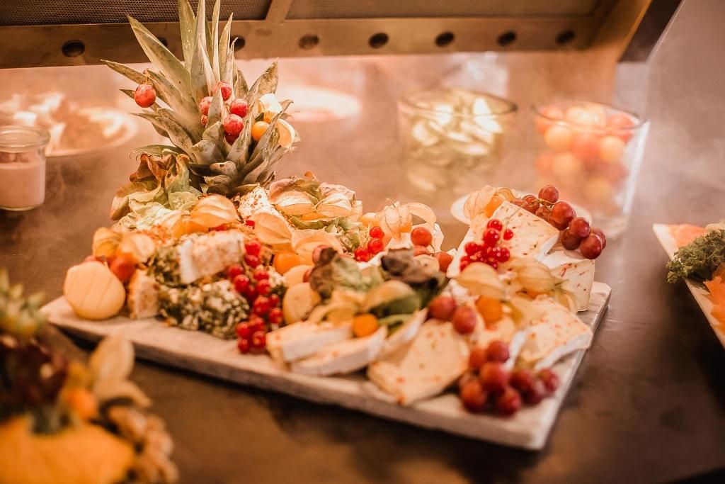 Een schaal met verschillende kazen en fruit op een tafel.