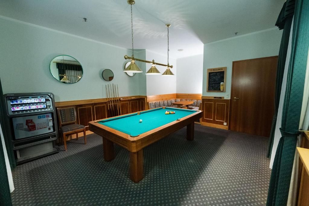 A pool table in a room with a wooden cabinet, a mirror, and a wall-mounted clock.