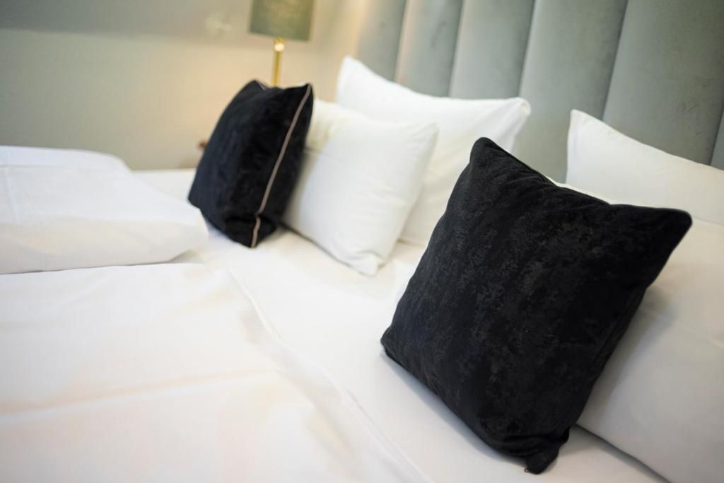 Una cama con ropa de cama blanca y dos almohadas negras.