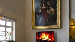 Amplia sala de estar con chimenea, dos sofás de cuero y un cuadro grande enmarcado en la pared.