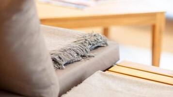 A wooden bench with a cushion and a blanket.