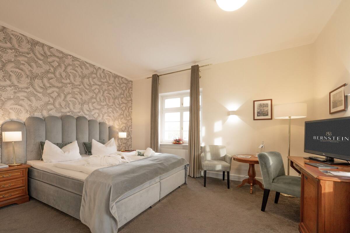 Une chambre d’hôtel avec un grand lit, un bureau avec un ordinateur, une chaise et un téléviseur.