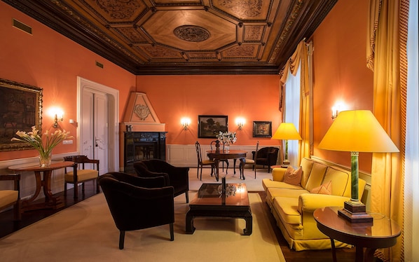 A room with a fireplace, a sofa, a table, and chairs. - Le Palais Art Hotel Prague (Prague)