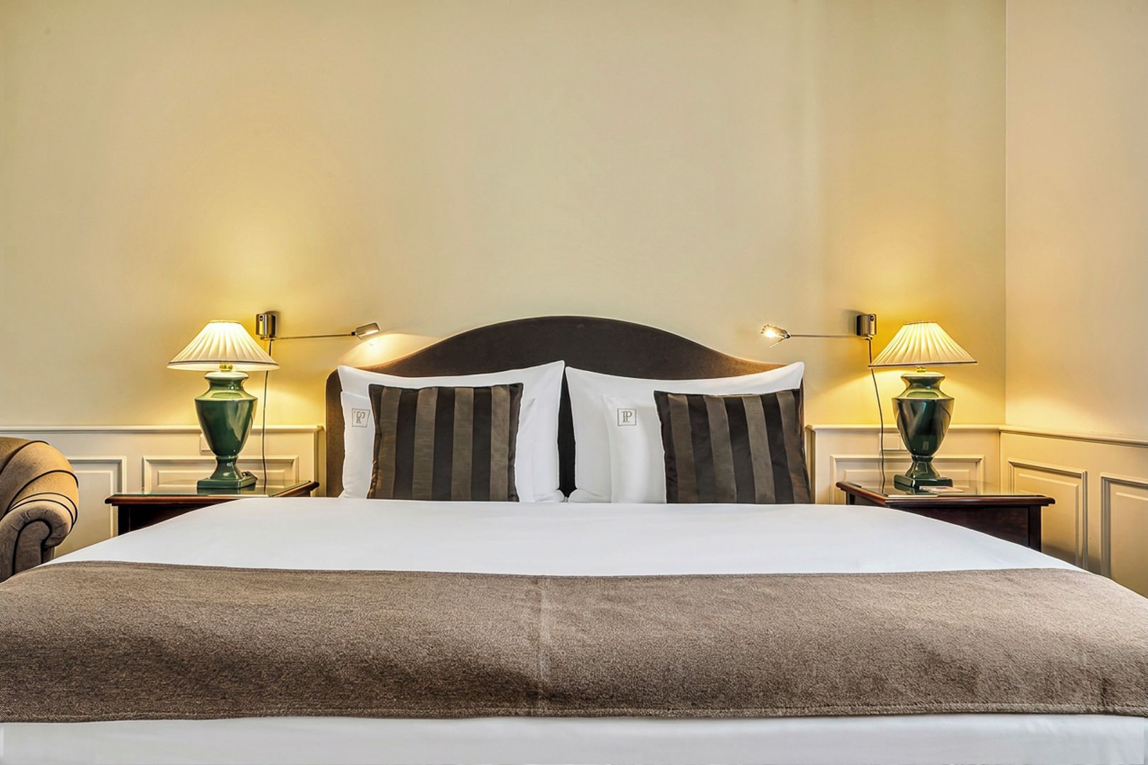 Una habitación de hotel con una cama grande, dos mesitas de noche y dos lámparas.
