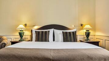 Una habitación de hotel con una cama grande, dos mesitas de noche y dos lámparas.