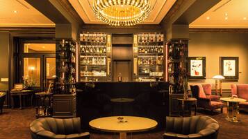 A bar area with a round table, leather chairs, and a chandelier.