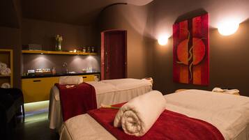 Een spa-ruimte met twee bedden, een wastafel en een spiegel.