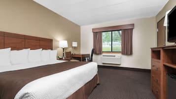 Habitación de hotel con una cama grande, un escritorio, una silla, un televisor y una ventana con cortinas.