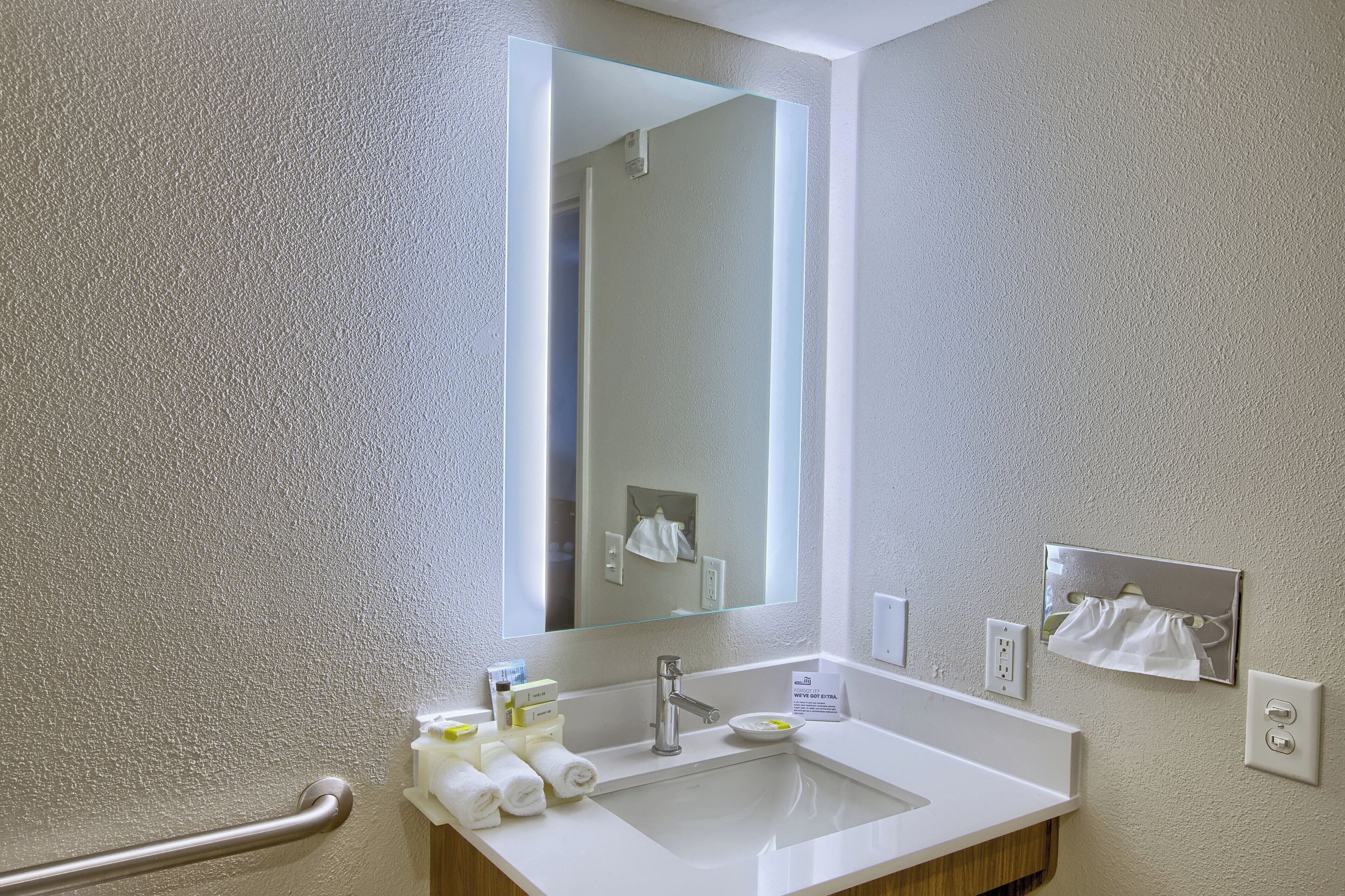 A bathroom with a white sink, a mirror, and a towel rack.