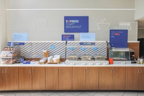 A breakfast buffet area with signs indicating 'EXPRESS START BREAKFAST', 'EGG-XACTLY THE START YOU NEED', and 'HOT FOOD'.