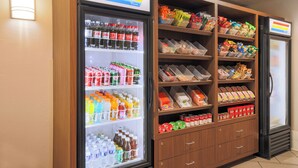 A vending machine stocked with beverages and snacks, including Coca-Cola and various other drinks and packaged foods.