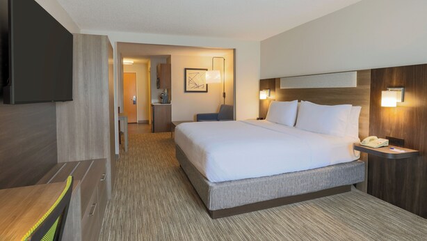 A hotel room with a large bed, bedside tables, a flat-screen TV, and a desk with a chair.