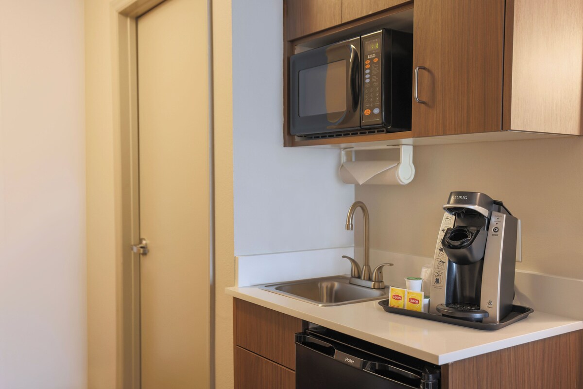A compact kitchenette with a microwave, coffee maker, and a sink.