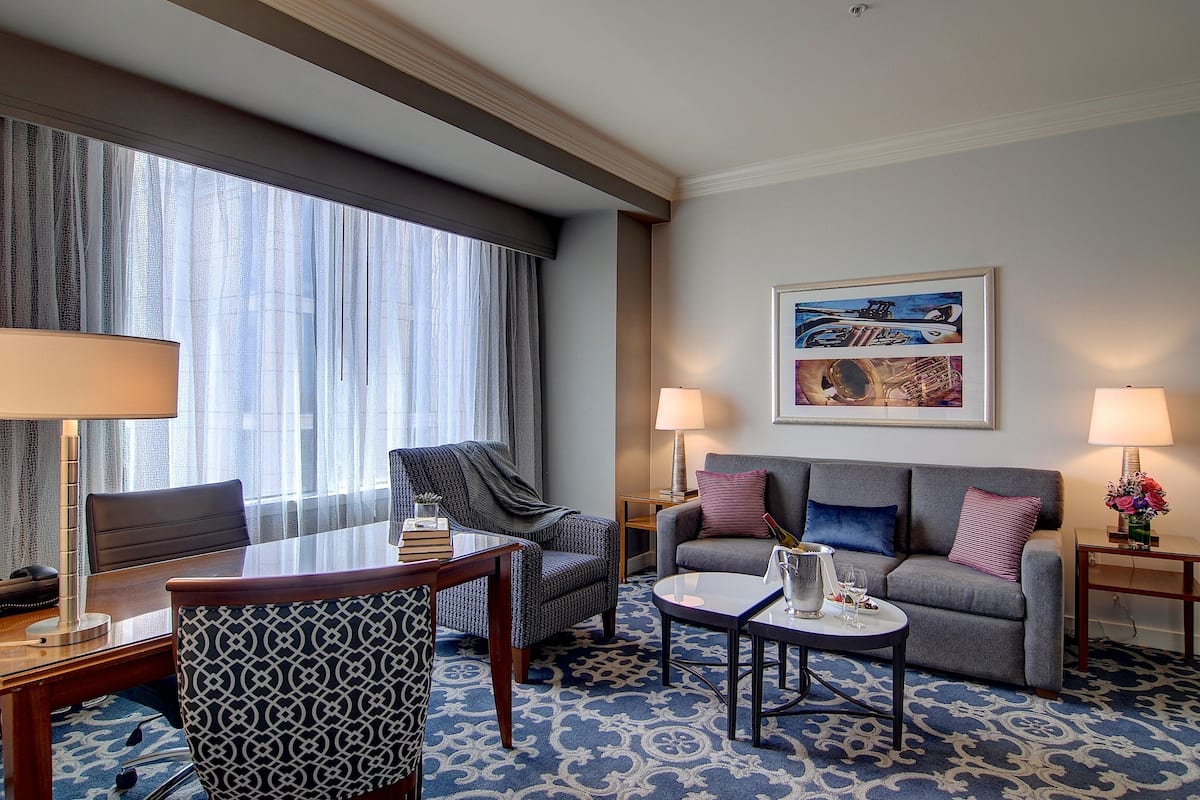 Une chambre d’hôtel comprenant une table à manger, deux fauteuils, un canapé, une table basse et un tableau au mur.